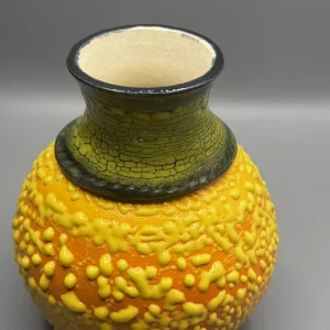 A layered surface caught between eruption and stillness — glowing yellows and volcanic tones suggest emotional heat carried beneath the surface. (view 3 of 4)