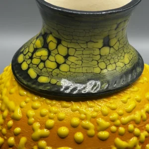 A layered surface caught between eruption and stillness — glowing yellows and volcanic tones suggest emotional heat carried beneath the surface. (view 4 of 4)